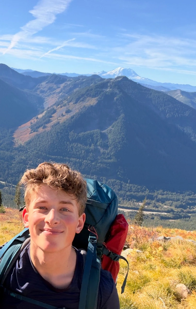 Benji smiling with a hiking backpack on a mountainside