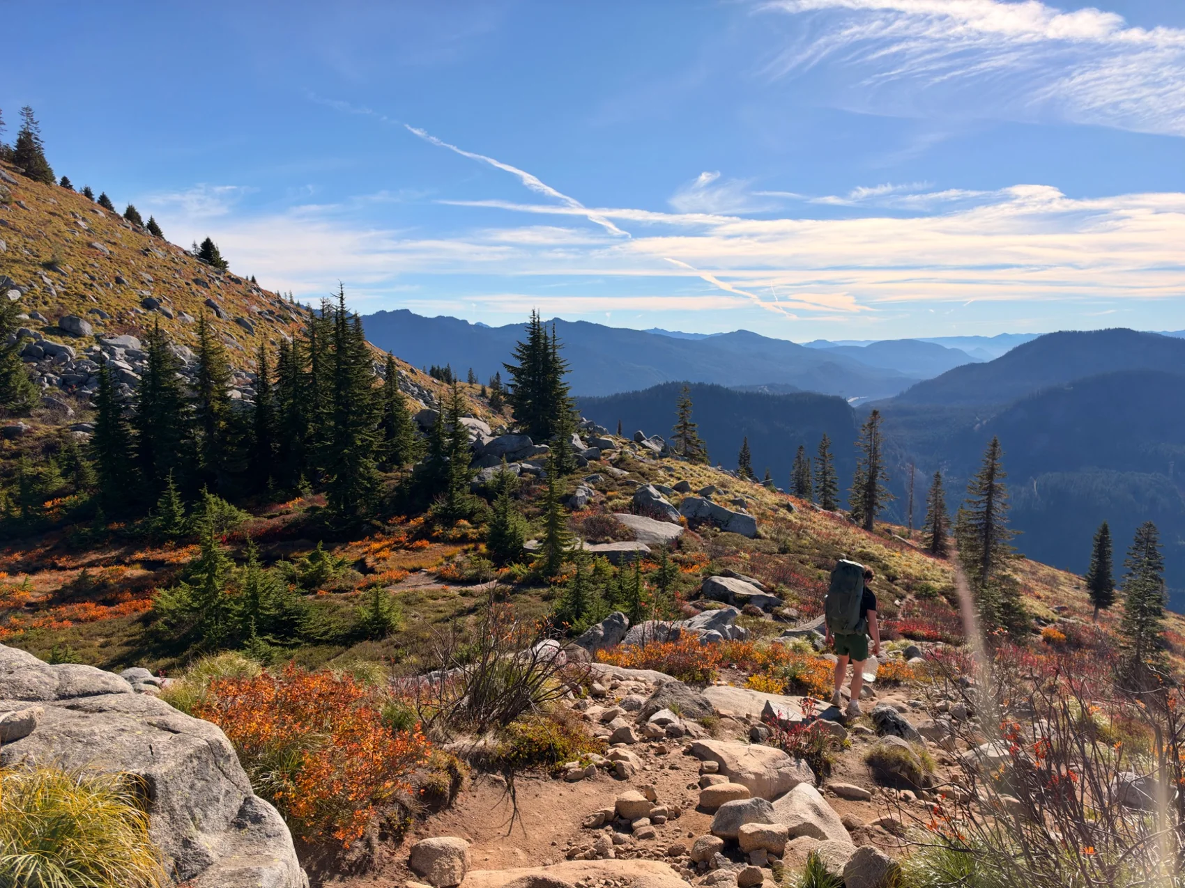 Personal landscape photograph of alpine hiking trails, evergreens and distant mountains under blue sky
